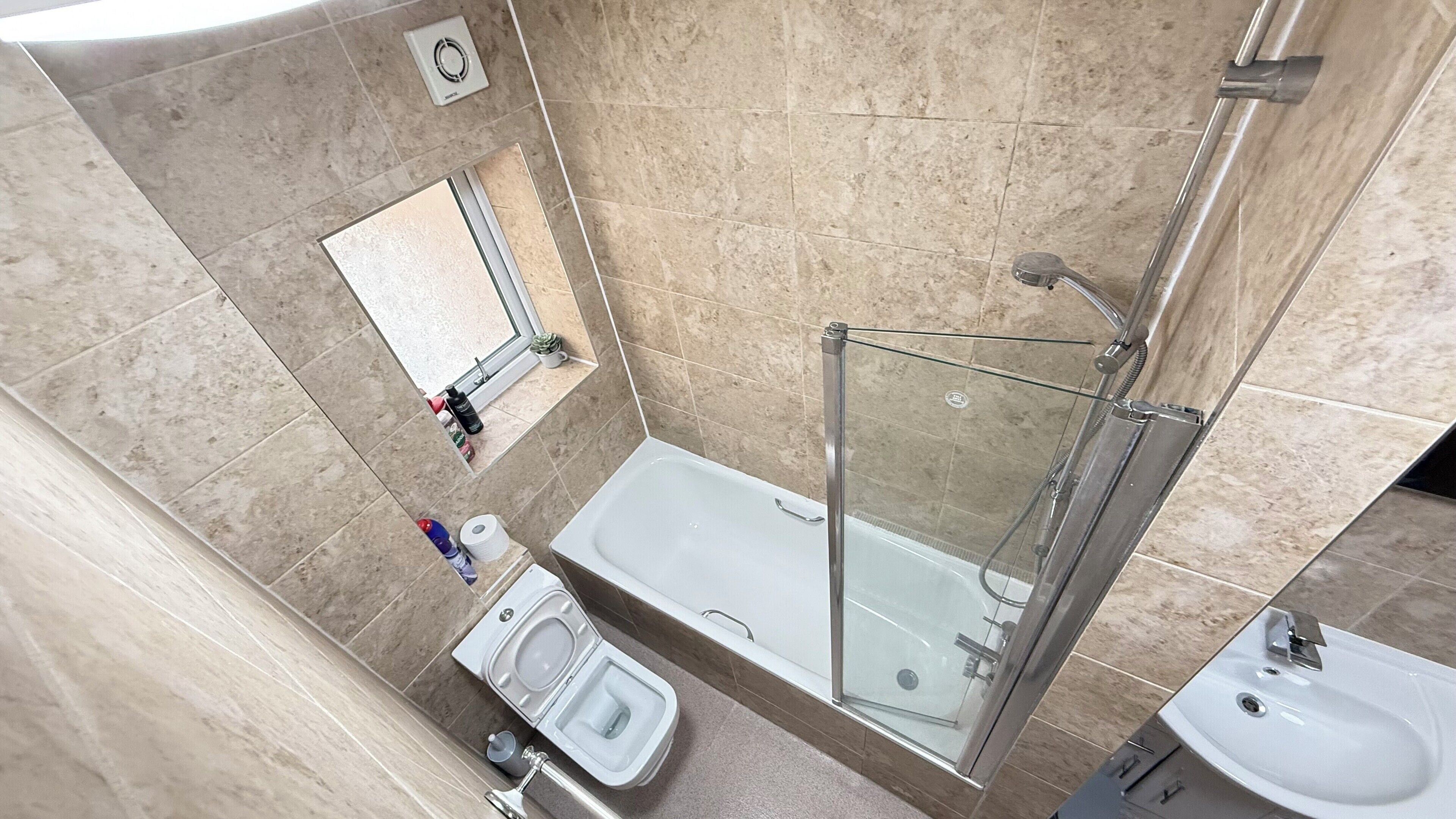 A modern bathroom with a glass-enclosed shower, a separate toilet, and a sink.