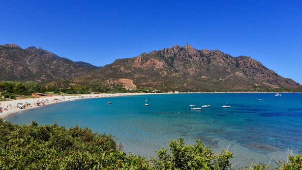 A coastal beach with clear blue waters, boats, and a mountainous backdrop. - Exceptional villa: 400 m²  for 15 people, with pool (Tertenia)