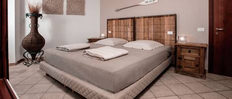 A bedroom with a large bed, bedside tables, a nightstand, a vase, and wall decor.