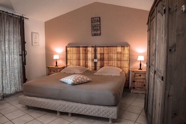 Un dormitorio con una cama grande, dos mesitas de noche con lámparas, un cabecero de madera y un letrero en la pared.