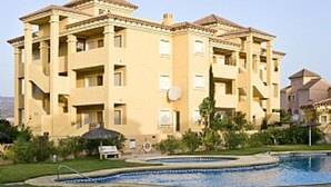 A multi-story hotel with a swimming pool, outdoor seating, and a landscaped garden. - First Floor Apartment On Golf Resort, Shared PoolWell Equipped Apartment (VERA)