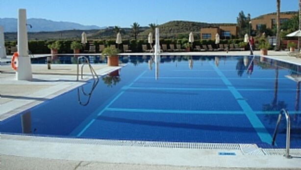 A swimming pool with clear blue water, surrounded by lounge chairs and potted plants. - First Floor Apartment On Golf Resort, Shared PoolWell Equipped Apartment (VERA)