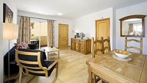 A room with a wooden dining table, a sofa, a TV, and a mirror. - First Floor Apartment On Golf Resort, Shared PoolWell Equipped Apartment (VERA)