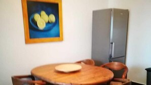 A dining area with a round wooden table and six chairs, a painting on the wall, and a refrigerator in the background. - Vacation apartment Kiefer in Hillscheid near Koblenz (Hillscheid)