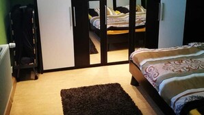 A bedroom with a bed, a dark rug, and a wardrobe with a colorful artwork. - Vacation apartment Kiefer in Hillscheid near Koblenz (Hillscheid)