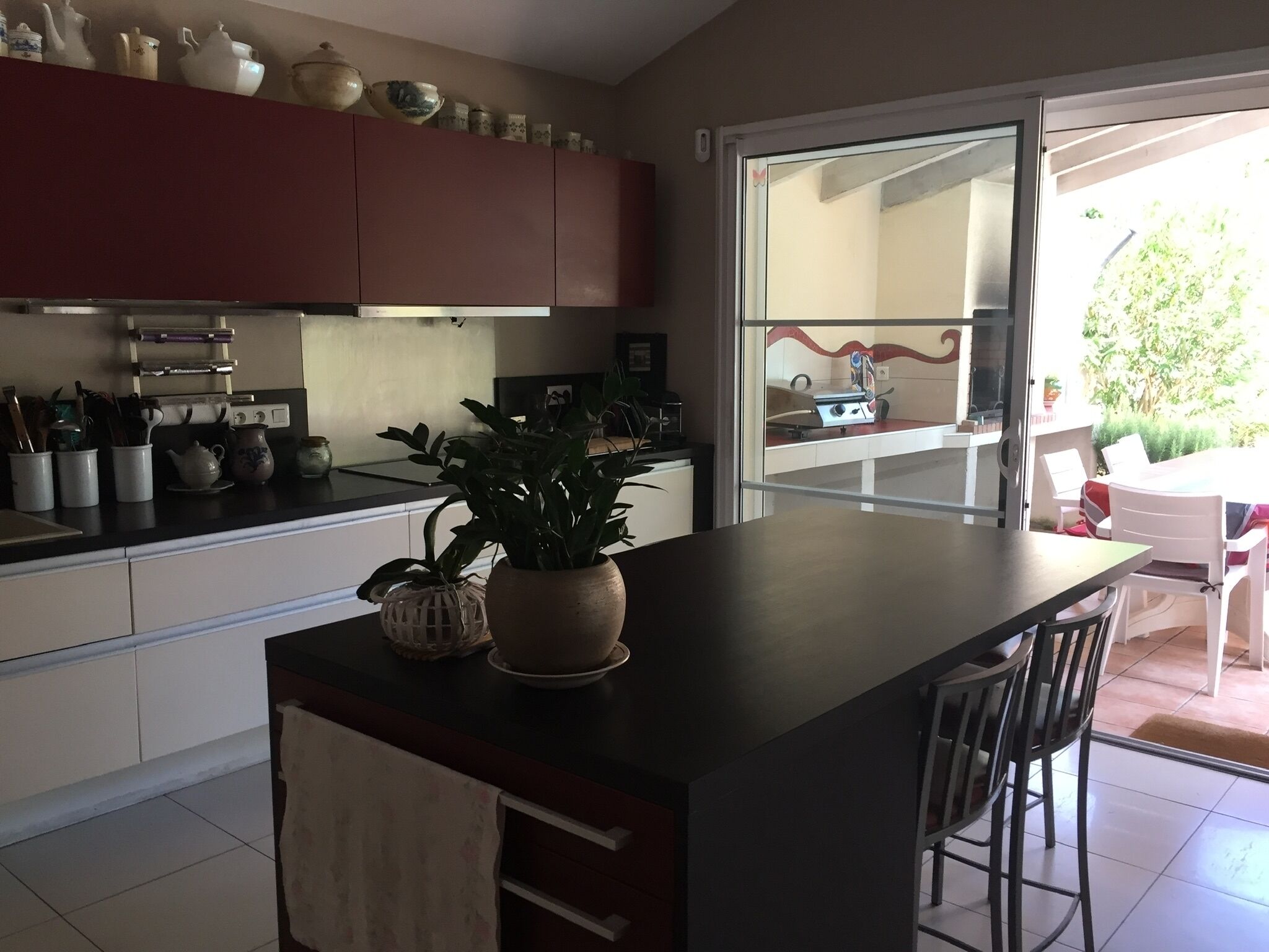 Una cocina con isla central, armarios blancos y un comedor con mesa y sillas.