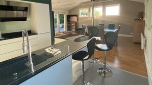 A modern kitchen with a central island, bar stools, and a dining area with a table and chairs. - Quiet house with garden - Golfe du Morbihan (Baden)