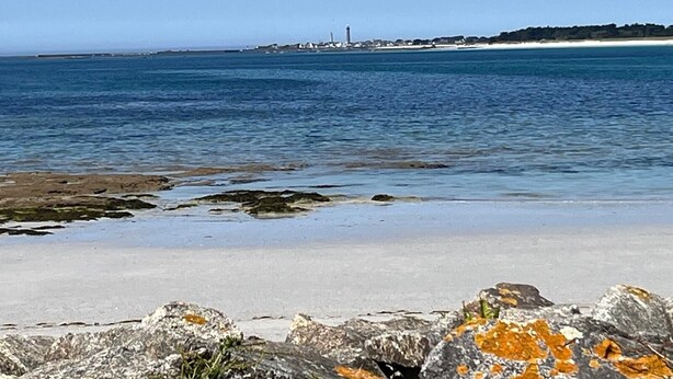A coastal beach with a lighthouse in the distance, rocky foreground, and clear blue sky. - Quiet house with garden - Golfe du Morbihan (Baden)