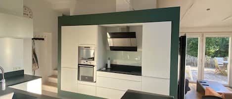 A modern kitchen with a skylight, built-in appliances, and a dining area with black chairs.