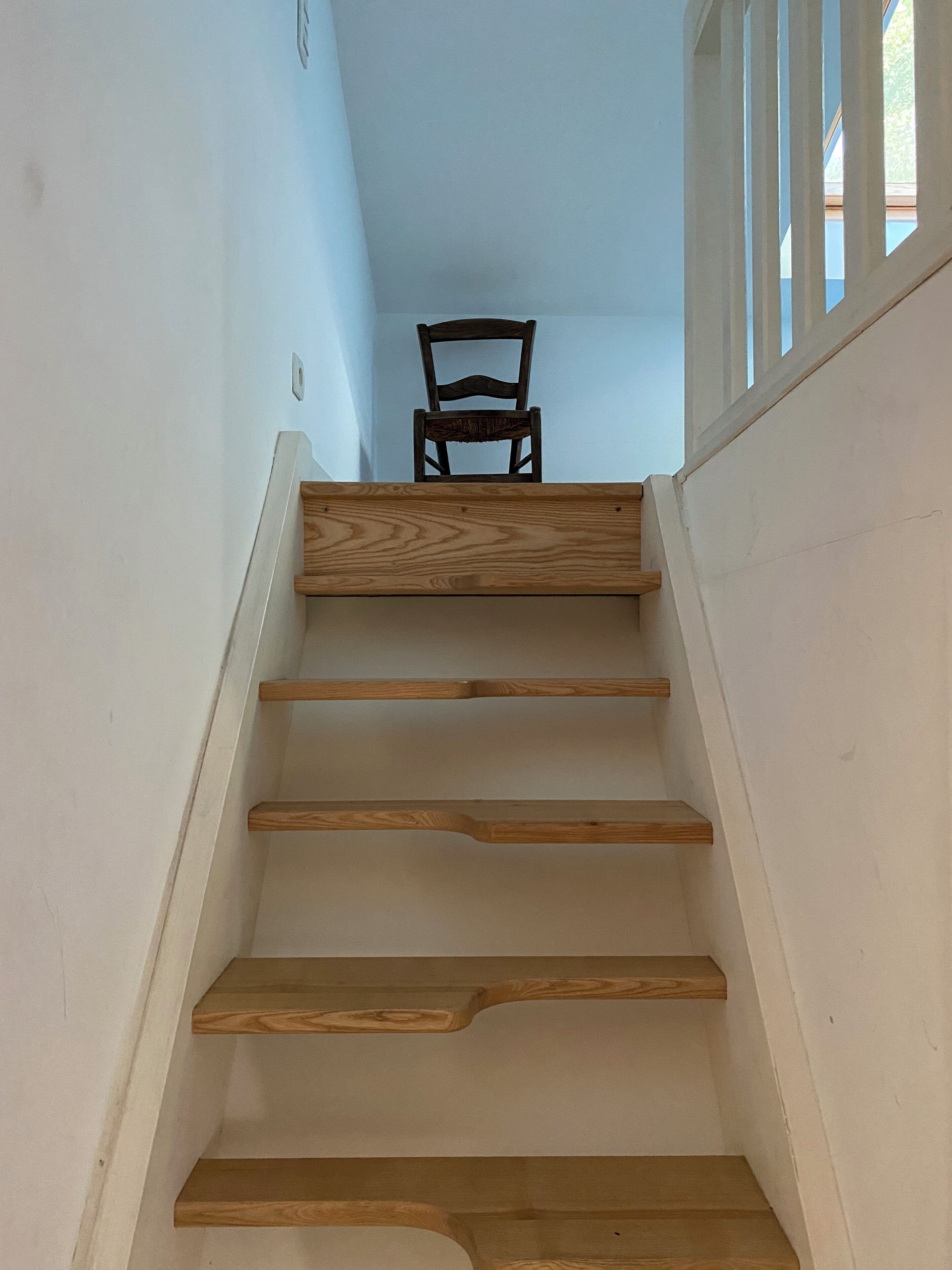 A wooden staircase with a chair at the top.