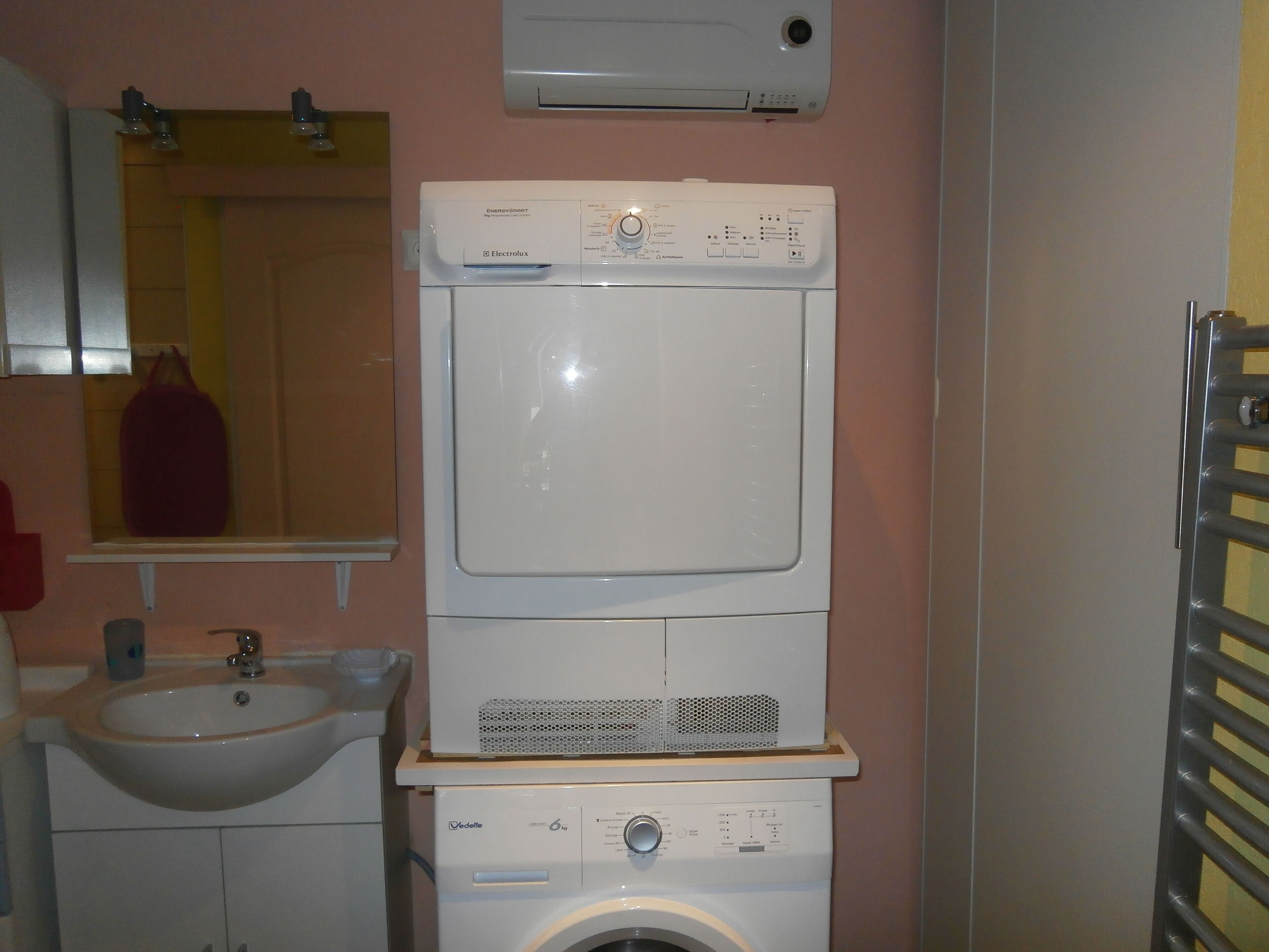 Un bagno compatto con lavandino, lavasciuga affiancata e specchio.