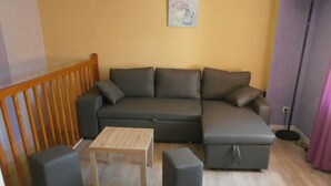 En moderne stue med en grå hjørnesofa, et træ sofabord og to matchende skraldespande.