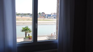 Blick aus einem Fenster auf einen Strand und Gebäude in der Ferne.