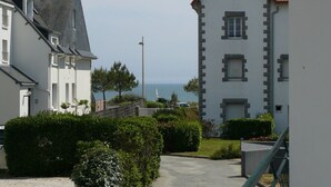Una zona residencial costera con edificios blancos, una vista despejada al mar y un sendero pavimentado.