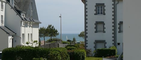 Ett bostadsområde vid kusten med vita byggnader, fri utsikt över havet och en asfalterad gångväg.
