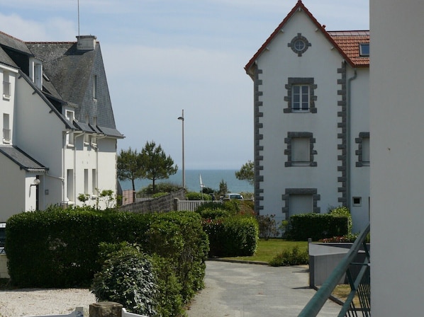 A coastal residential area with white buildings, a clear view of the sea, and a paved pathway. - KERPOUM - Apartment in holiday rental 300 m from the beach, Carnac - D29 (Carnac)