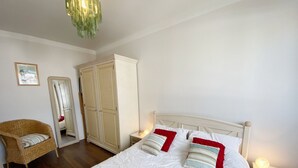 Un dormitorio con cama, mesita de noche, silla, armario y espejo.