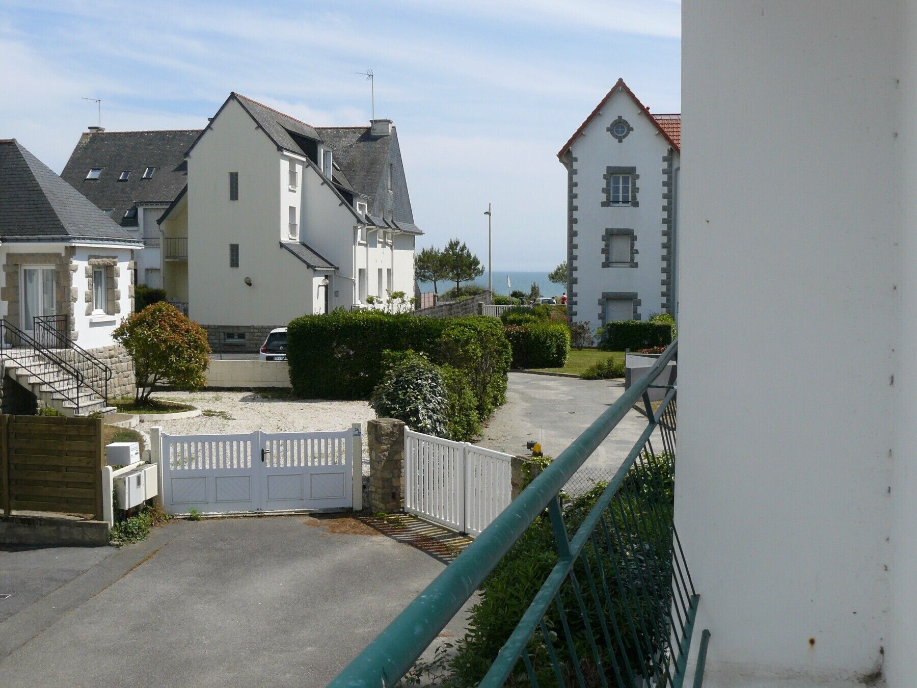 Ett bostadsområde med hus, en uppfart med grind och utsikt över havet.