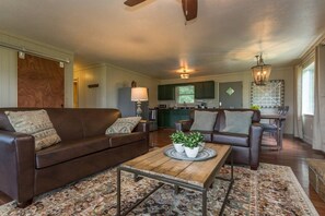 A living room with a brown leather sofa, a coffee table with decorative items, and a patterned rug. - Ultra Views Of Great Smoky Mountains & Mt. LeConte (Gatlinburg)