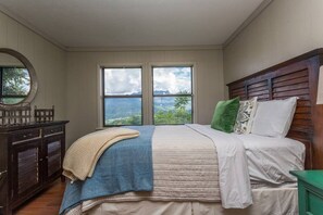 Ein Schlafzimmer mit einem großen Bett, einem Schminktisch, einem Spiegel und Blick ins Freie.