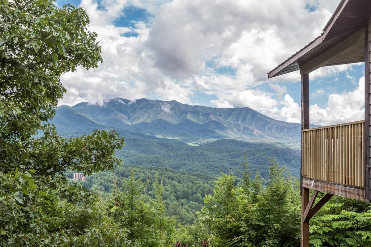 Une cabane en bois dotée d’un balcon donnant sur un paysage montagneux.
