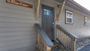 A wooden house with a gray door, a wooden staircase, and a sign that reads "Ultra View".
