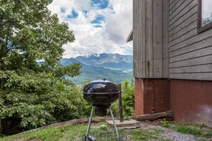 Un barbecue installé à l’extérieur, avec une vue sur les montagnes en arrière-plan.