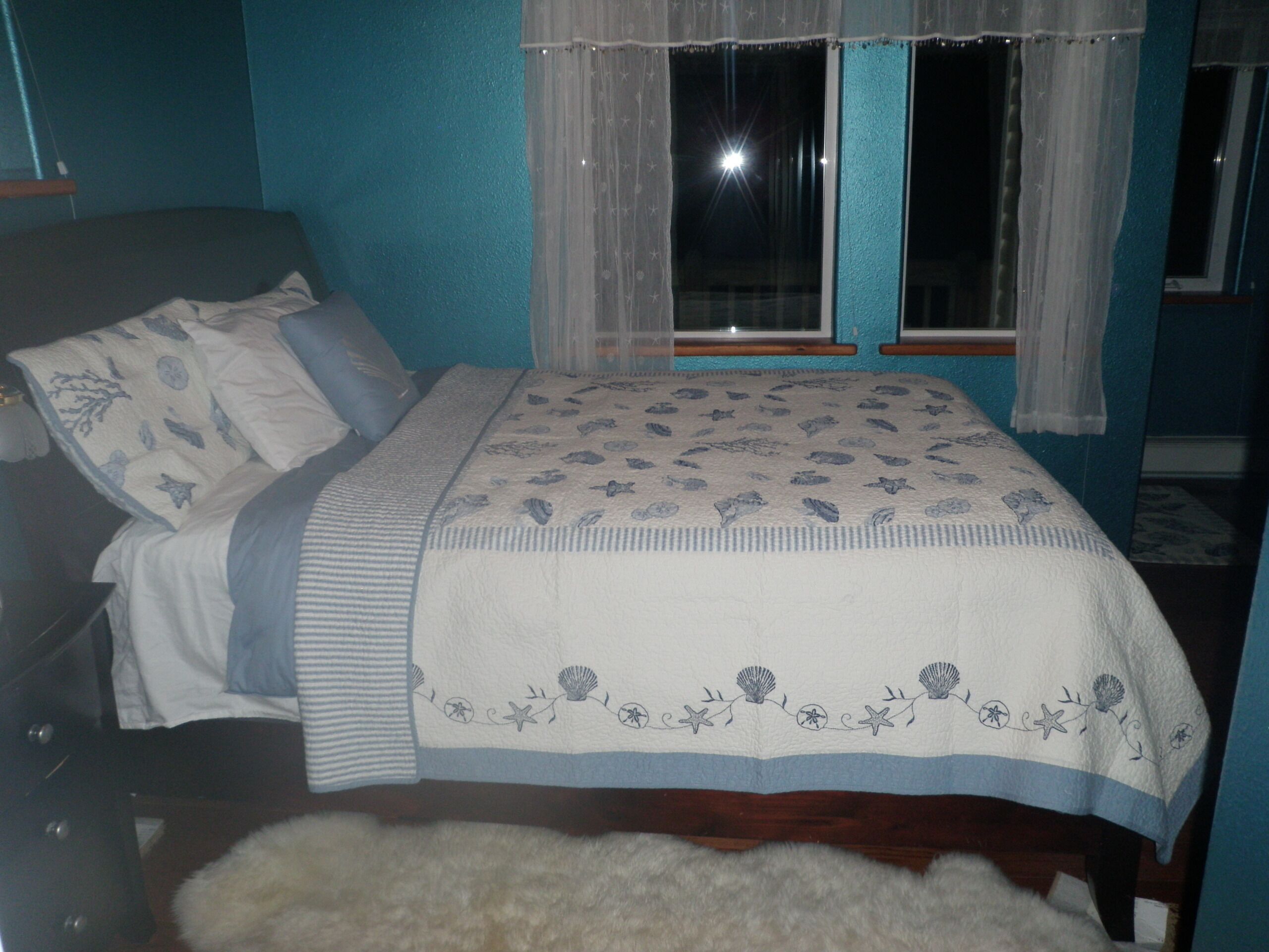 Un dormitorio con cama, cómoda y ventana con cortinas.