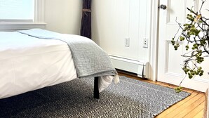 Ein Schlafzimmer mit Bett, Teppich mit Muster, Fenster und Tür.