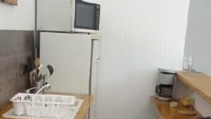 Une cuisine de taille réduite, dotée d’un plan de travail en bois, d’un évier et d’un four à micro-ondes.