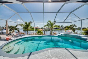Ein Swimmingpool mit klarem, blauem Wasser, umgeben von Liegestühlen und Palmen.