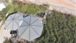 Vue aérienne d’un complexe hôtelier comprenant un grand bâtiment octogonal, une plage et un toboggan aquatique.