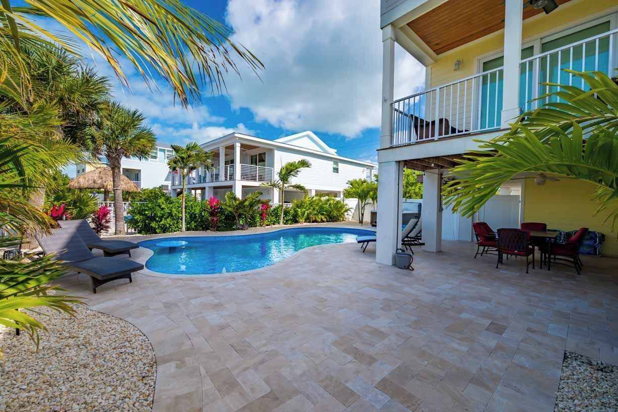 Una piscina rodeada de sillones de descanso y una zona de comedor con mobiliario exterior.