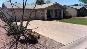 Una casa residencial con porche delantero, entrada para coches y un cactus en primer plano.