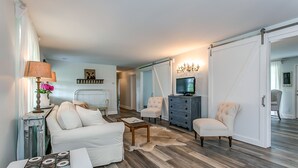 A living room with a white sofa, two armchairs, a coffee table, a TV, and a chandelier. - Cozy Cottage located in Franklin, TN on a 6 Acre Mini Farm (Franklin)