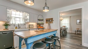 A kitchen with a wooden island, bar stools, and a hanging light fixture. - Cozy Cottage located in Franklin, TN on a 6 Acre Mini Farm (Franklin)