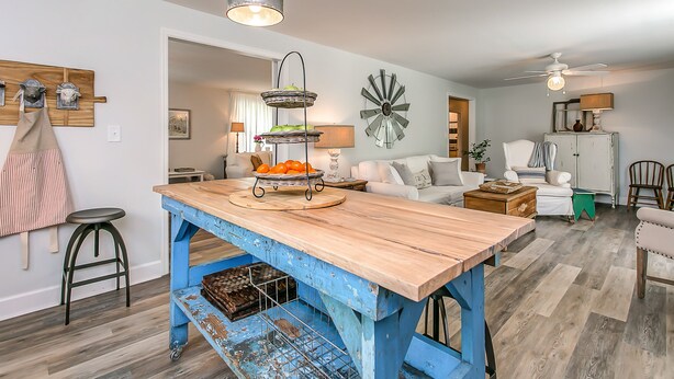 A spacious kitchen with a wooden island, a dining area with a white sofa, and a ceiling fan. - Cozy Cottage located in Franklin, TN on a 6 Acre Mini Farm (Franklin)