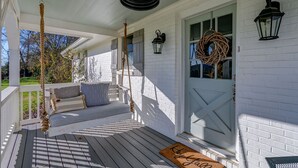 A porch with a swing, a bench, and a door with a wreath. - Cozy Cottage located in Franklin, TN on a 6 Acre Mini Farm (Franklin)