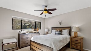 A bedroom with a bed, a nightstand, a dresser, a window, and a ceiling fan. - Country Club Bungalow, Sleeps 4 (Flagstaff)