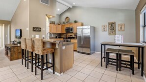 A modern kitchen with wooden cabinets, stainless steel appliances, and a bar area with stools. - Country Club Bungalow, Sleeps 4 (Flagstaff)