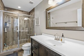 A modern bathroom with a glass-enclosed shower, a white sink, and a large mirror. - Country Club Bungalow, Sleeps 4 (Flagstaff)