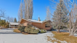 A house with a snow-covered driveway, a well-maintained lawn, and a clear blue sky. - Country Club Bungalow, Sleeps 4 (Flagstaff)
