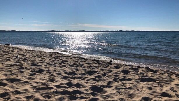 Een strand met een heldere lucht en een rustige zee.