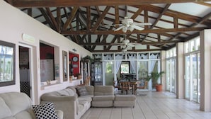 Ein geräumiger Wohnbereich mit hoher Decke und Holzbalken, ausgestattet mit Sofas und einem Esstisch.
