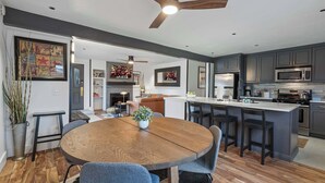 A modern kitchen with dark cabinets, a central island, and a dining area with a round wooden table and chairs. - Newly renovated 2BR Downtown, Main St, PCMR (Park City)