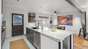 A modern kitchen with a large island, stainless steel appliances, and a dining area with a table and chairs. - Newly renovated 2BR Downtown, Main St, PCMR (Park City)