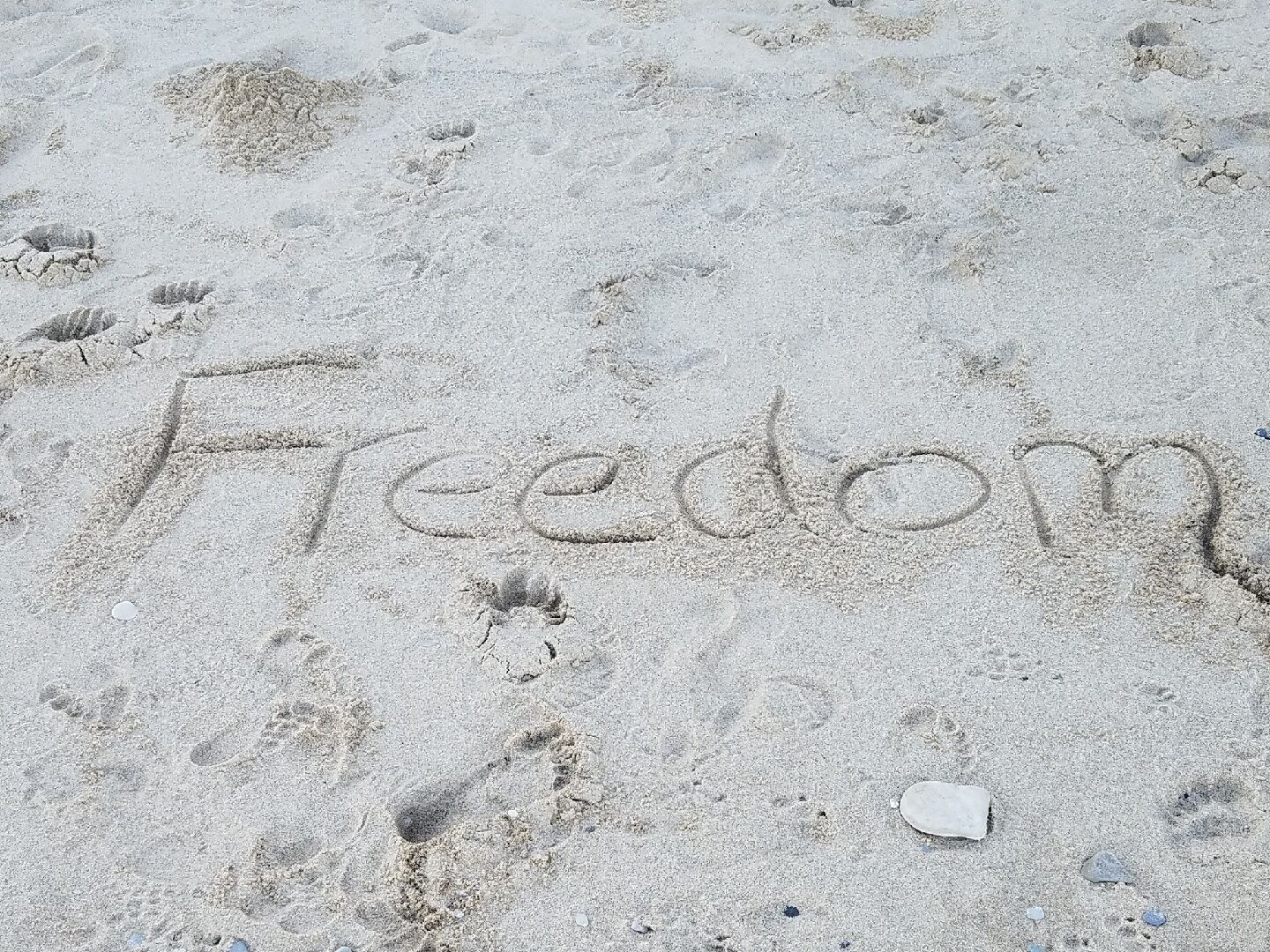 Footprints and the word "Freedom" written in the sand.