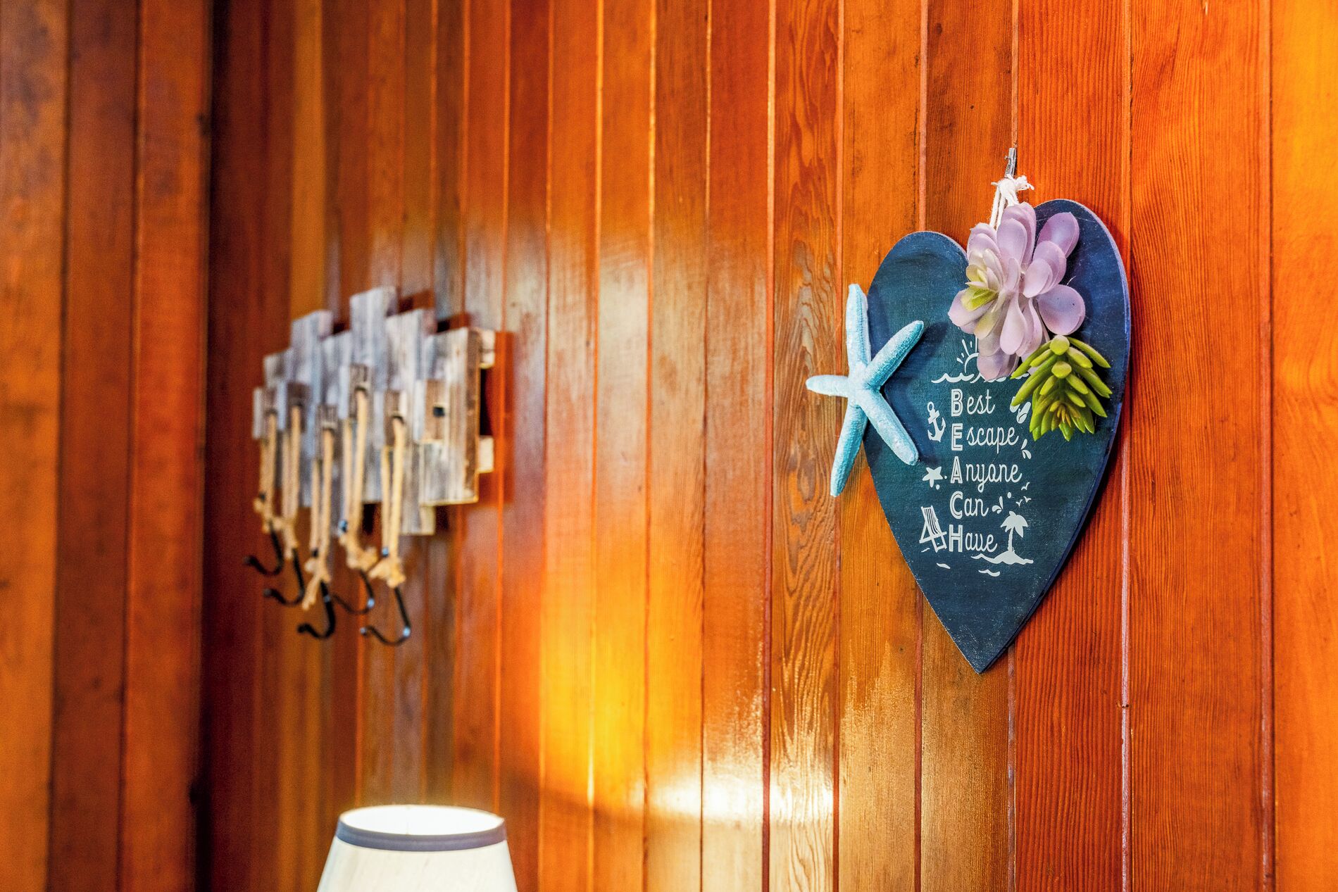 Een houten wand met een hartvormig bord waarop staat 'Best Escape Anyone Can Have' en een sleutelhanger met sleutels.