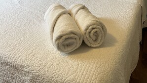 A neatly made bed with white linens and two rolled towels placed on the bed. - Cozy updated 3 BR home steps away from downtown, space to relax and enjoy.  (Holland)