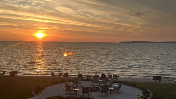 A sunset view over a calm sea with outdoor seating and a grassy area. - Cozy updated 3 BR home steps away from downtown, space to relax and enjoy.  (Holland)